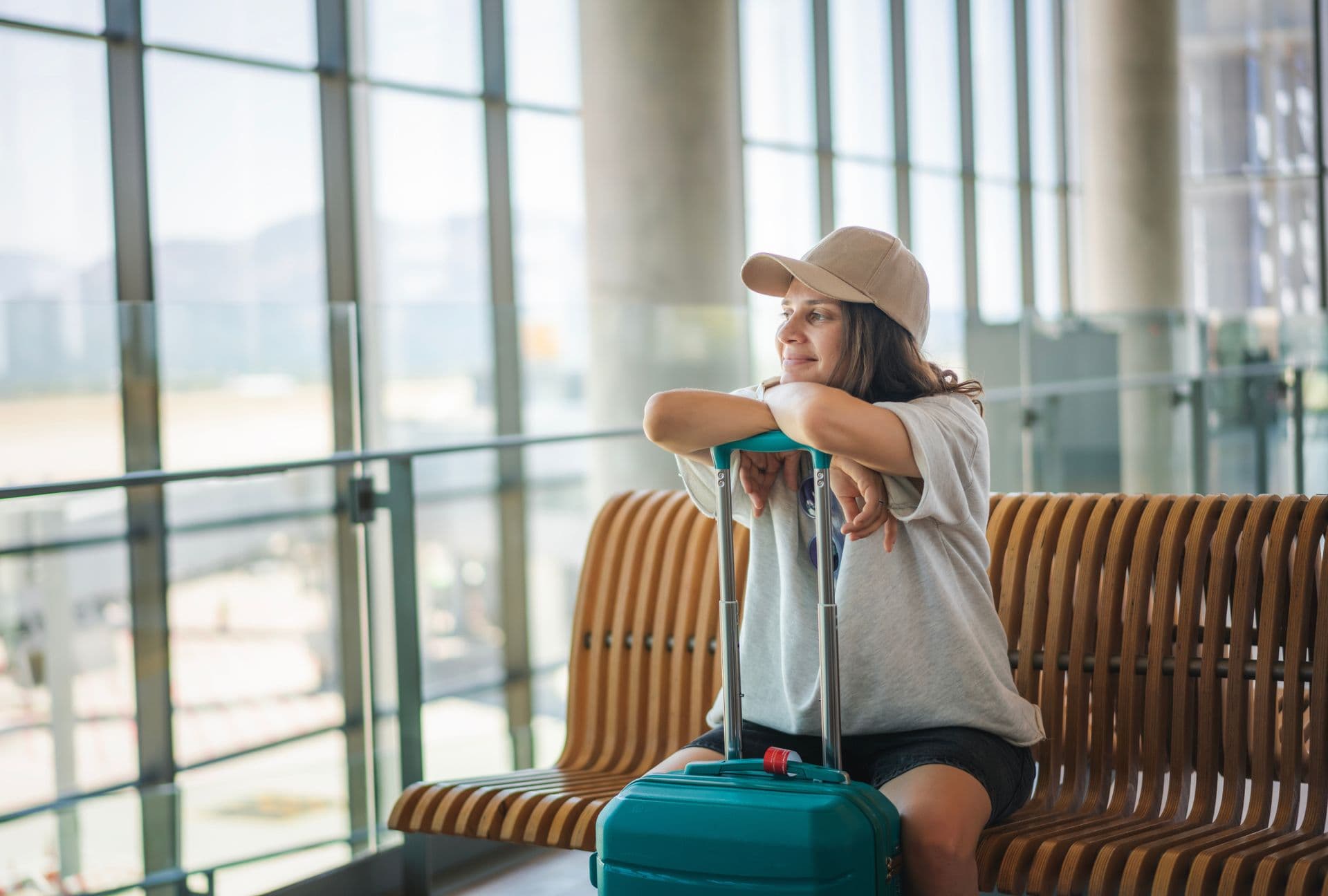 Intercambista sentada no aeroporto ao lado da mala de viagem