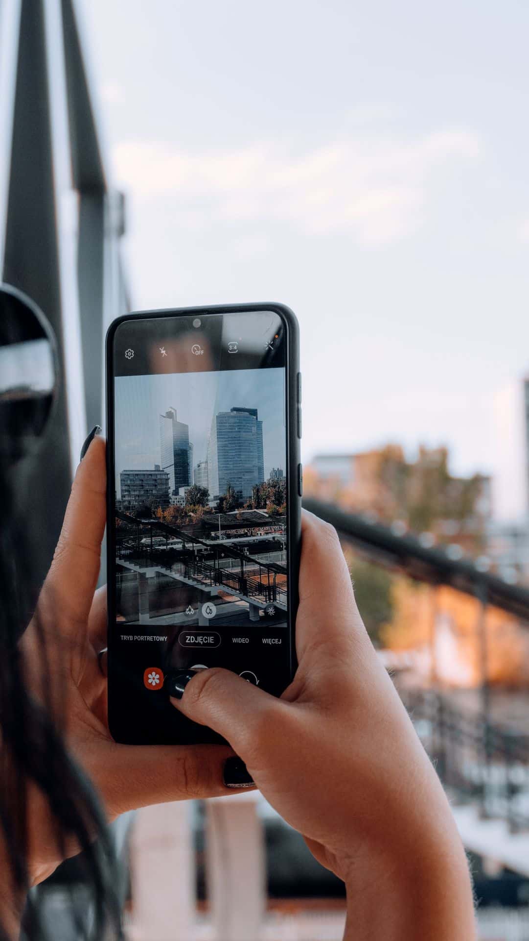 Celular fotografando arranha-céus de uma cidade europeia