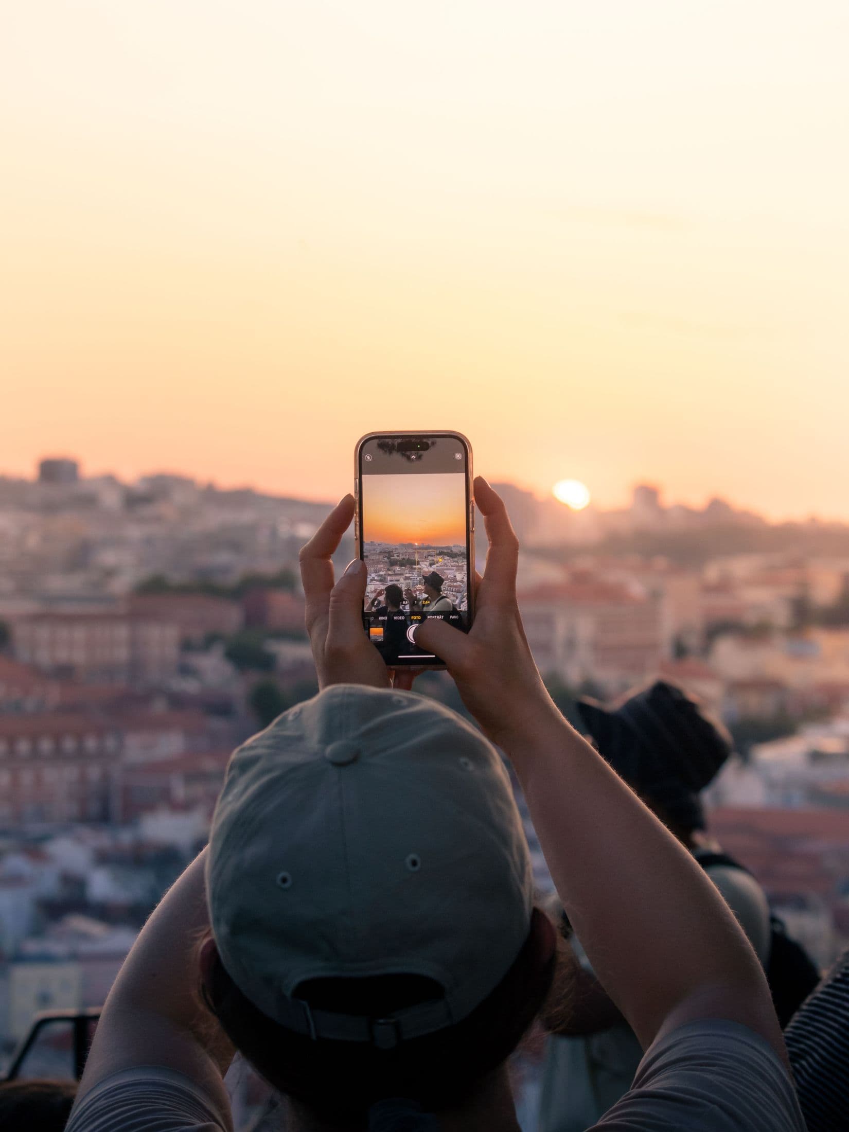 Intercambista fotografando o pôr do sol sobre a cidade com o celular