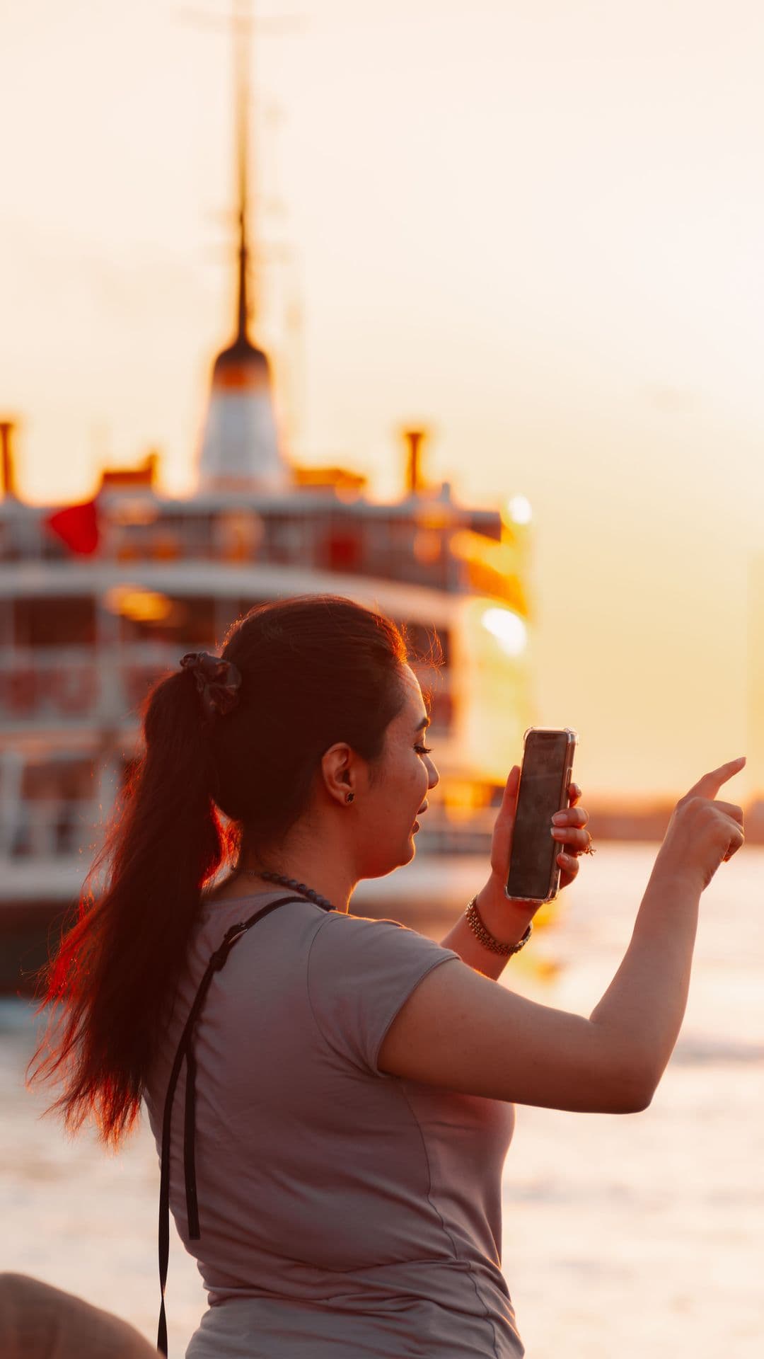 Intercambista fotografando balsa no pôr do sol com o celular